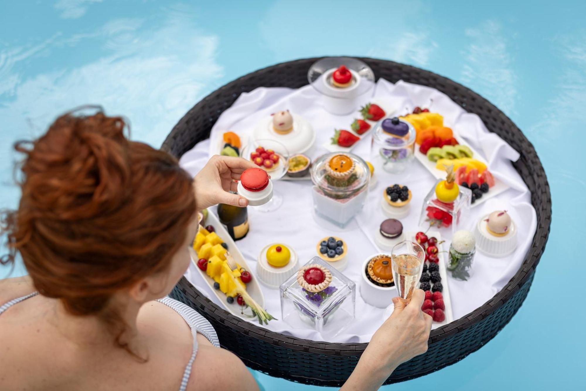 Rogner Hotel Tirana Exterior photo A woman selecting a dessert from a poolside buffet